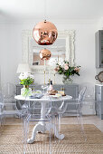 Round dining table and designer chairs in front of pale grey sideboard in open-plan kitchen