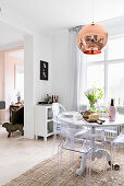 Round dining table and designer chairs in front of window in open-plan kitchen