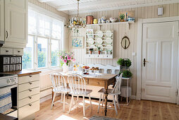 Rustic table, bench and chairs next to window in bright kitchen-dining room