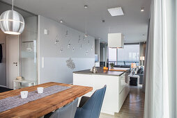 Dining table, kitchen island and couch in elongated open-plan interior