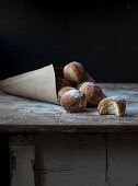 Fresh beignets near set of baked loaf in craft paper with powdered sugar