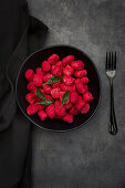 Beetroot gnocchi with sage in a black bowl on a grey surface