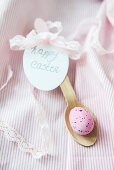 Pink Easter egg on wooden spoon with tag