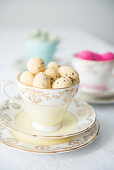 Pale yellow quail eggs in vintage collectors' cup