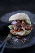 A bread roll with pork knuckle and salad