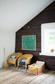 Two children's chairs below chalkboard on rustic wooden wall