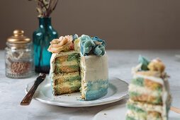 Portion of rainbow cake, filled with chantilly cream, and decorated with buttercream flowers