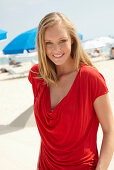 A blonde woman on a beach wearing a red top