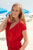 A blonde woman on a beach wearing a red top