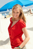 A blonde woman on a beach wearing a red top