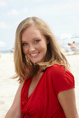 A blonde woman on a beach wearing a red top