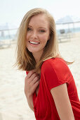 A blonde woman on a beach wearing a red top