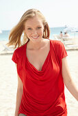 A blonde woman on a beach wearing a red top