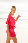 Blonde Frau in rotem Kleid am Strand