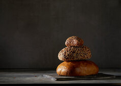 Two breads and a bread roll, stacked against a dark background