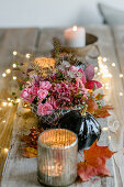 Tischgesteck mit Rosen und Windlichtern