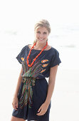 A young blonde woman with necklace wearing a beach dress