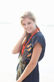 A young blonde woman with necklace wearing a beach dress