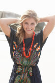 A young blonde woman with necklace wearing a beach dress