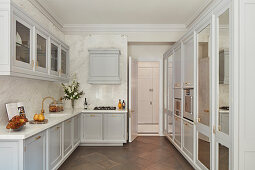 Elegant kitchen with grey panelled cabinets and glass-fronted wall units