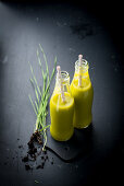 Mango and wheatgrass smoothies in glass bottles