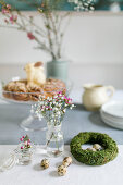 Wreath of moss, quail eggs and spring flowers in jars