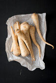 Fresh parsnips on paper and a black background