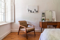 Retro dressing table with mirror and upholstered armchair in corner of room