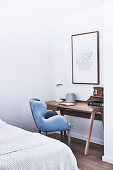 Narrow wooden wall table for the home office with light blue velvet chair in the corner of the bedroom