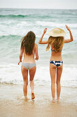 Two women wearing bikinis and summer hat on the beach