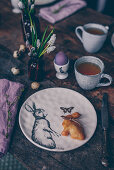 A table laid for an Easter breakfast with tea and an Easter bunny bun