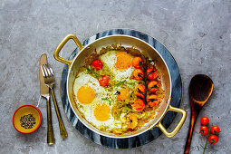 Frying pan with breakfast Fried eggs, onion and tomatoes