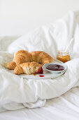 Frühstück im Bett mit Croissants und Marmelade