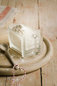 Mehl in Glasbehälter auf Holzteller mit Porzellanlöffel