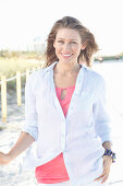 A young woman outside wearing a pink top and a light shirt blouse