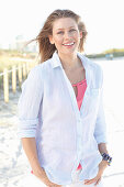 A young woman outside wearing a pink top and a light shirt blouse