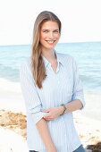 A young woman by the sea wearing a light blue shirt