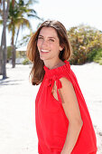 A brunette woman outside wearing a red top