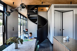 Boy at the dining table in front of the spiral staircase in the open architect's house