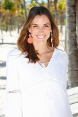 A brunette woman outside wearing a white blouse