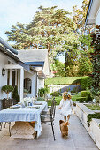 Mädchen und Hund neben antikem Steintisch auf Terrasse am Haus