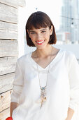 A brunette woman wearing a white long-sleeved blouse