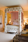 Himmelbett mit Chintz-Vorhängen in olivgrünem Schlafzimmer eines englischen Herrenhauses