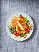 Parmesan escalope on a bed of tomatoes and rocket