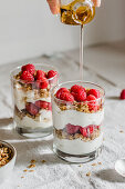 Granola with greek yougurt, raspberries and honey in a glass