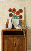 Bild mit Blumenmotiv und Schale mit Lametta auf Retro Schränkchen