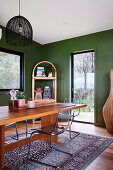 Plastic chairs on wooden table in dining room with green walls