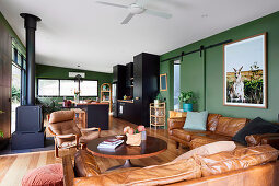 Offener Wohnraum mit grünen Wänden und Ledermöbeln