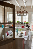 View through kitchen door to table with slip-covered chairs