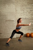 A young woman performing a stretching exercise with arms and one leg stretched